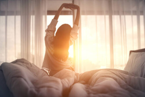ベッドで朝日を浴びる女性
