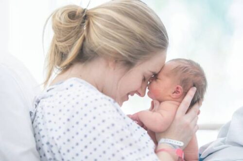 生まれた赤ちゃんの額と自分の額をくっつける女性